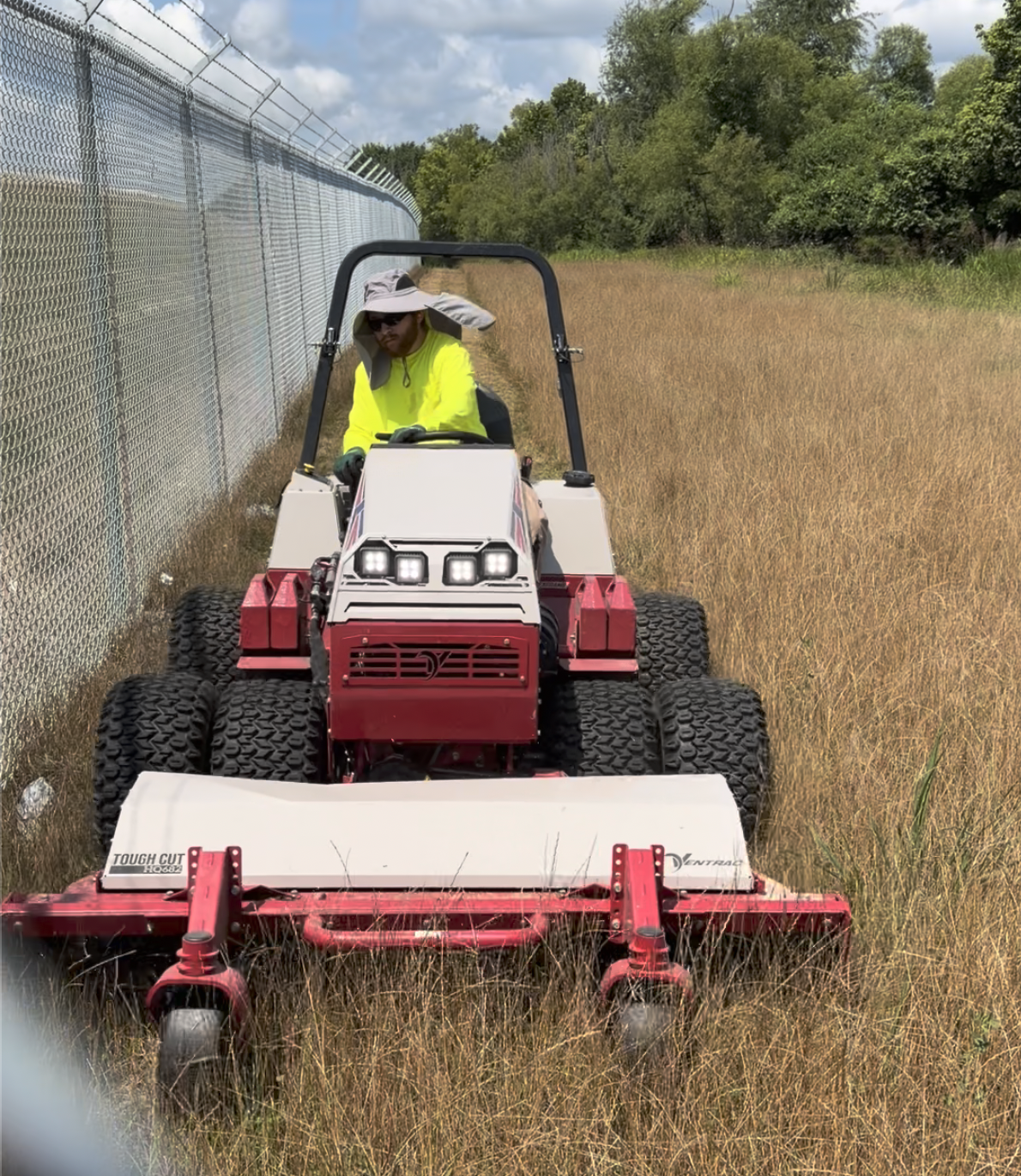 Operator mowing overgrown field on a ventrac mower