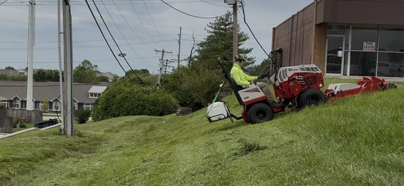 Operator mowing overgrown brush on a steep hillside