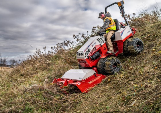 Operator mowing a steep grass hillside with all-terrain equipment